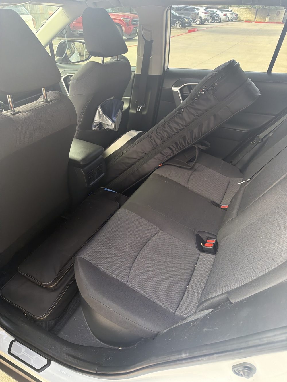 Back seat with pedalboard on the floor and guitar case on the seat