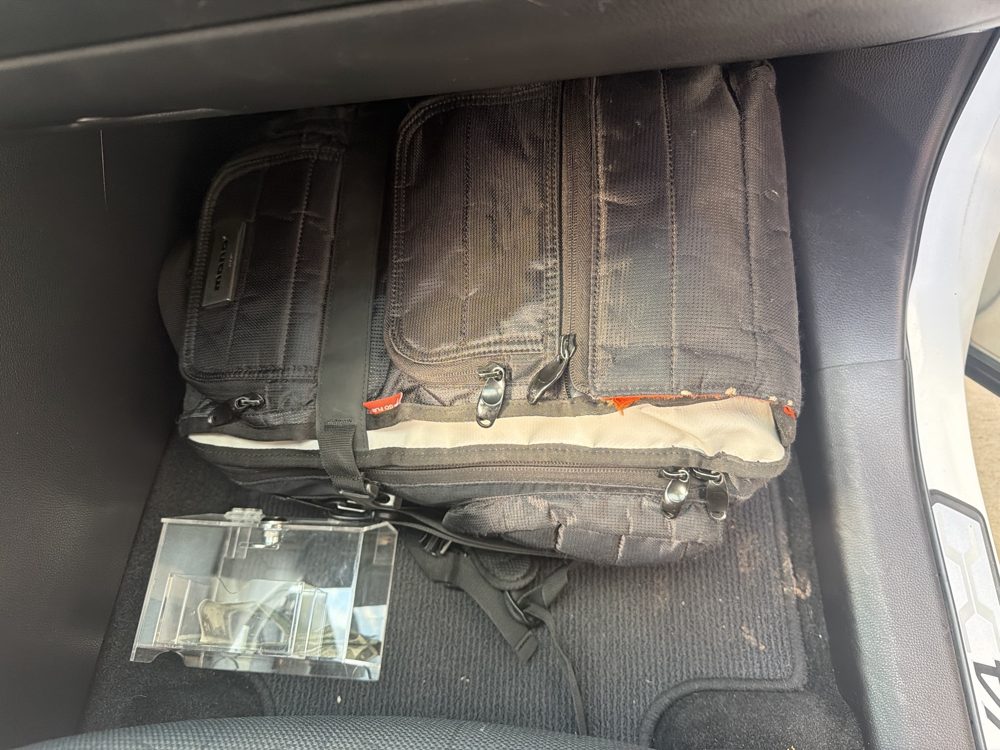 Mono backpack on the passenger foot rest with the tip box on the floor mat in front of it.